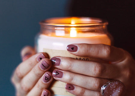 Hand holding a lit candle with a dark background